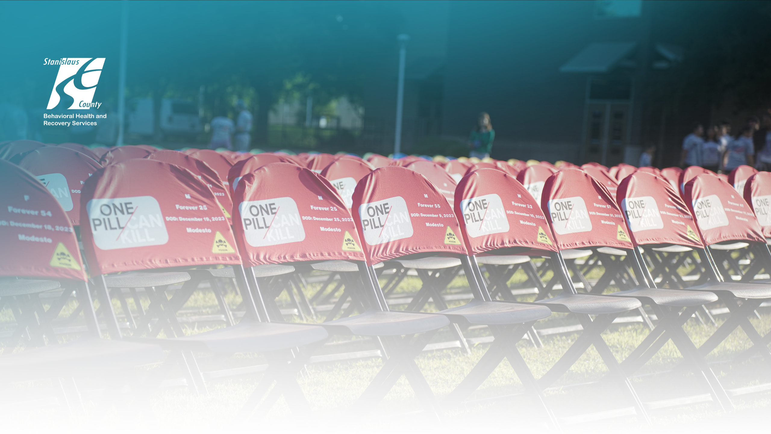 Rows of red chairs outdoors with “One Pill Can Kill” messages, set up for a fentanyl awareness community event by Stanislaus County Behavioral Health and Recovery Services.